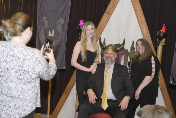 Three people pose on a Viking-style throne at the 2024 Auction.